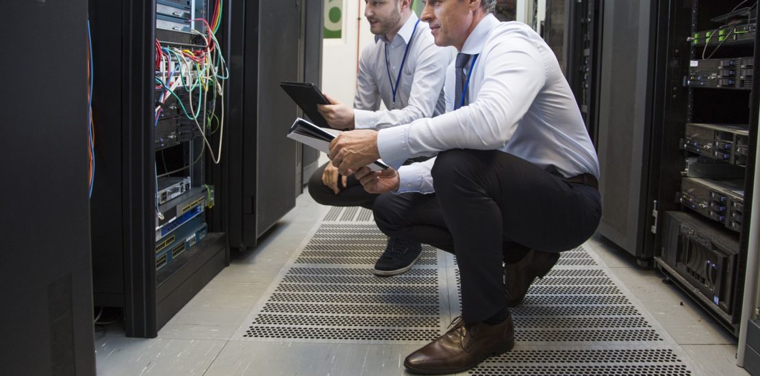 two male supervisors checking the inside of a data cabinet