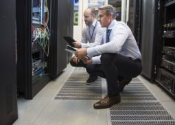 two male supervisors checking the inside of a data cabinet