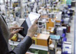 a woman using a tablet looking down on a factory floor