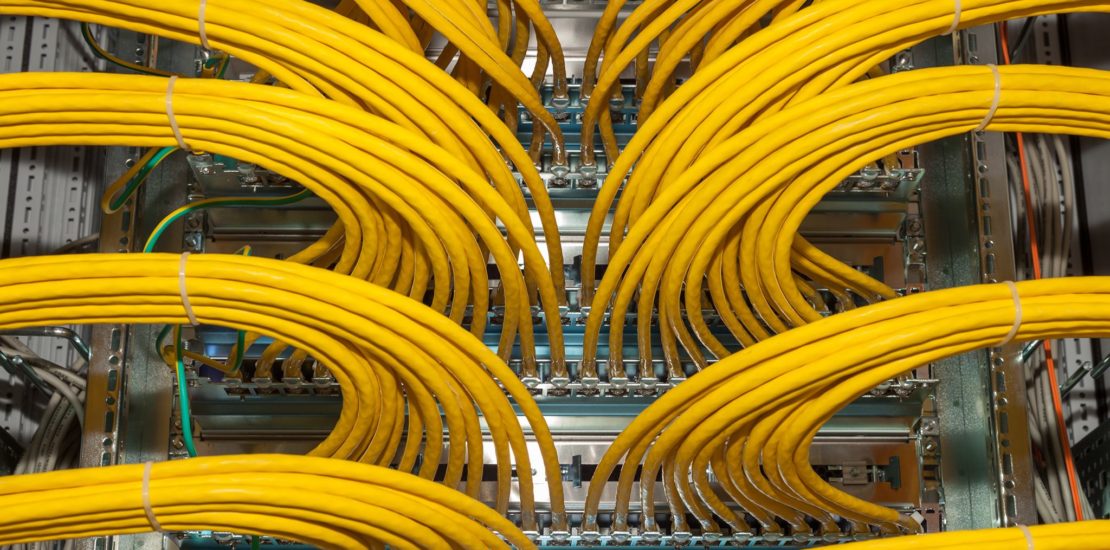 lots of yellow network cables plugged into server rack